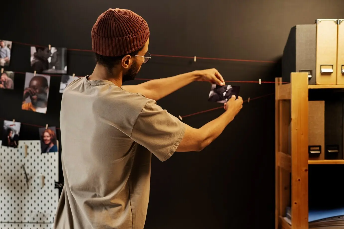 Vista lateral de un hombre revelando fotos en un cuarto oscuro.