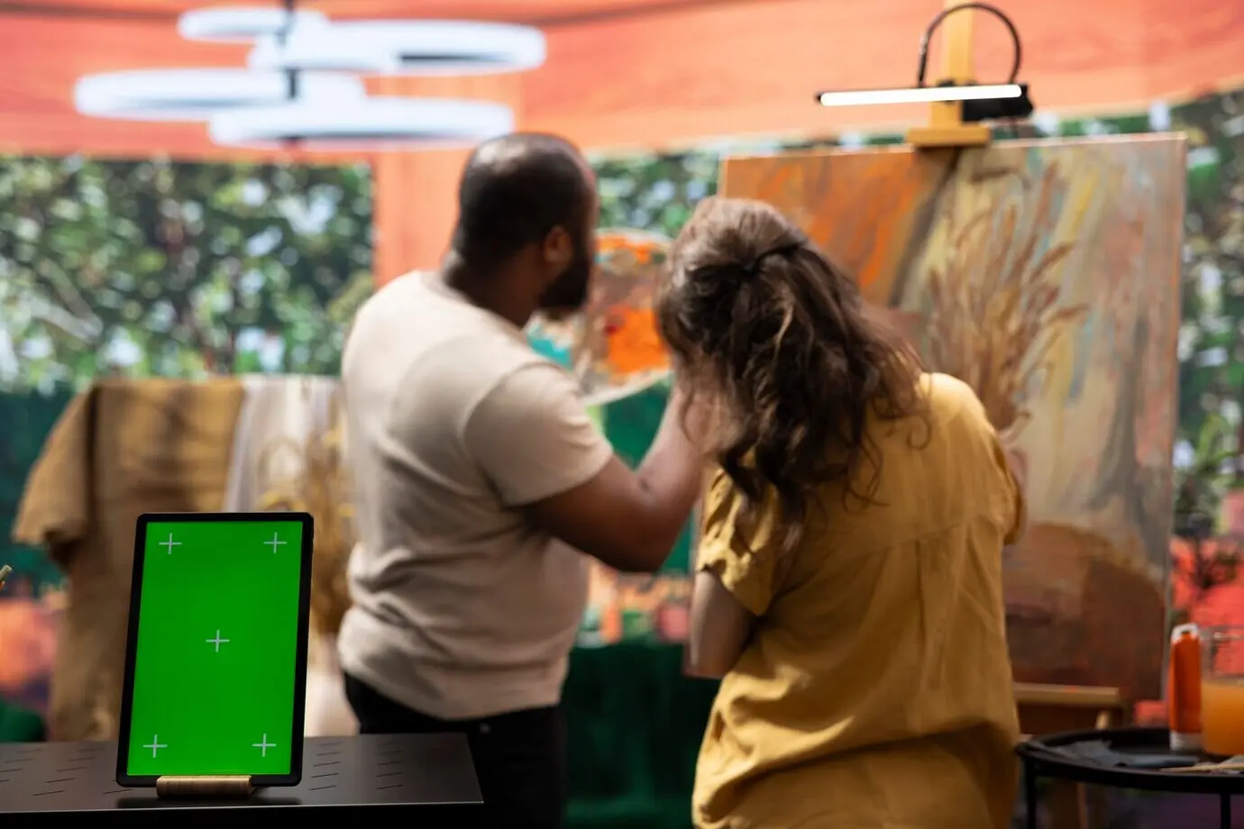 Pintores habilidosos trabajan en una creación artística junto a una pantalla de chroma key.